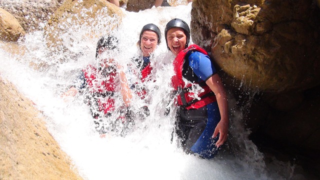Two happy whitewater rafting customers smiling below a waterfall in the river