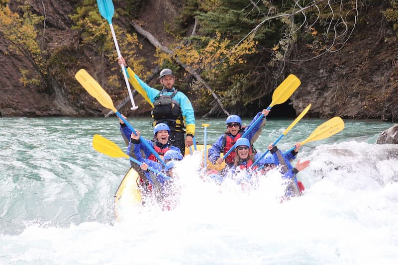 rafting group lifting their hands and paddles in celebration of finalization of rapids tour