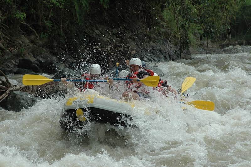 A rafting group going downstream through the rocky river amid turmoil water